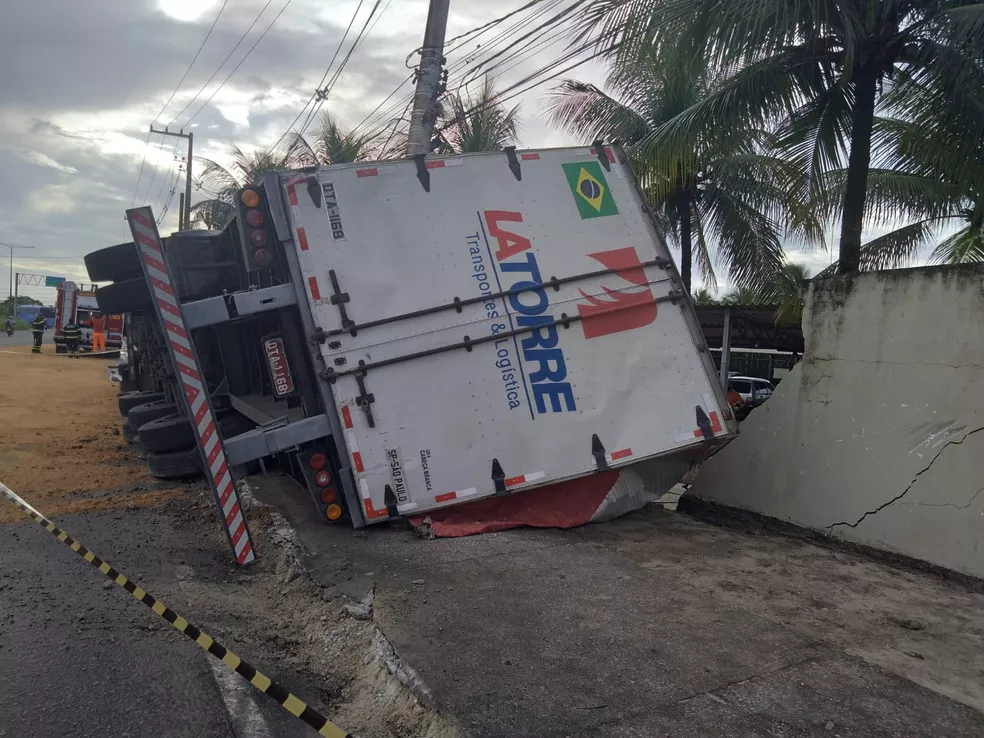 Caminhão carregado com balas e pirulitos tomba em curva e derruba muro de fábrica na Grande Natal